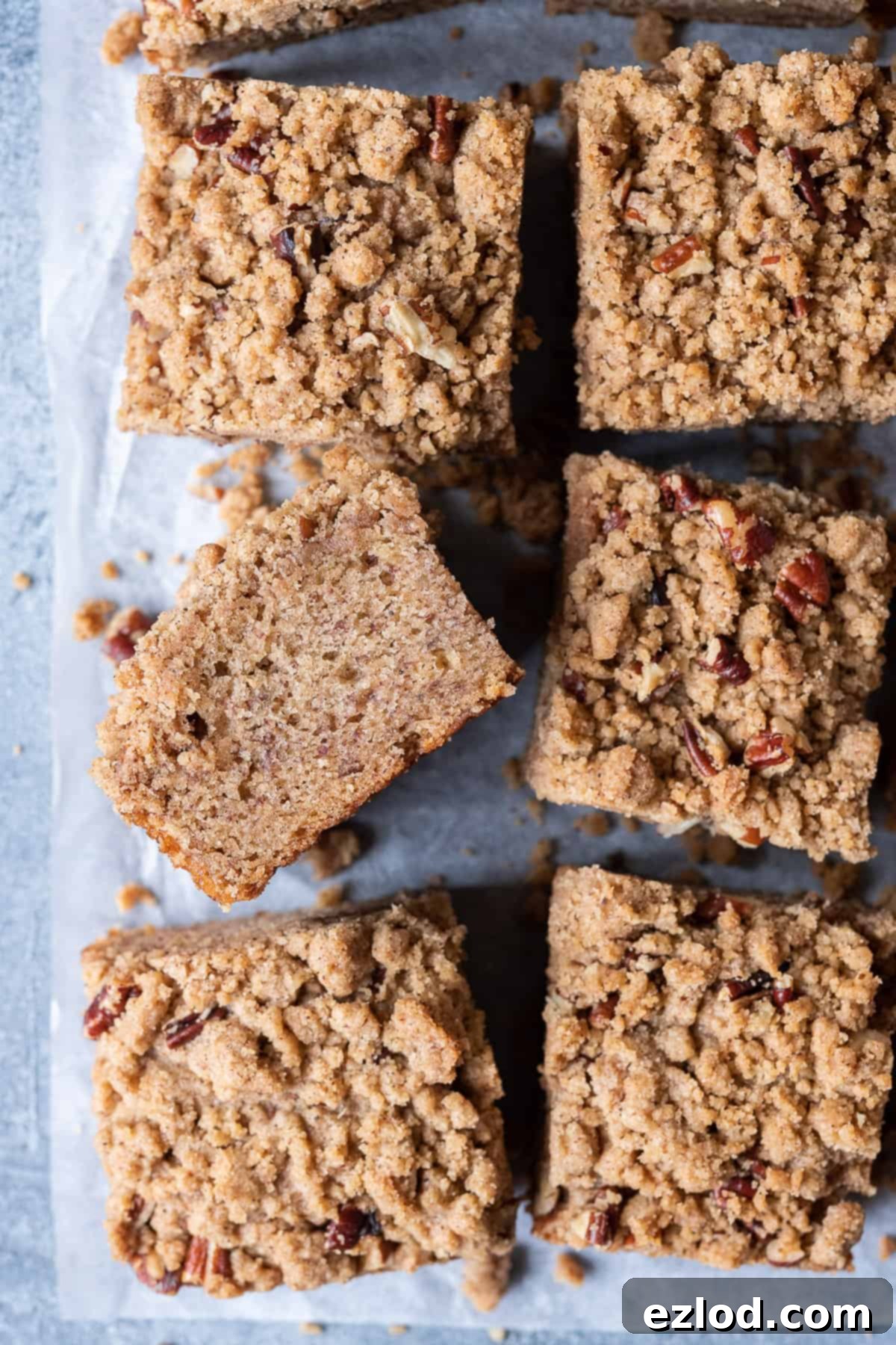 Squares of vegan banana crumb cake on a sheet of baking parchment.