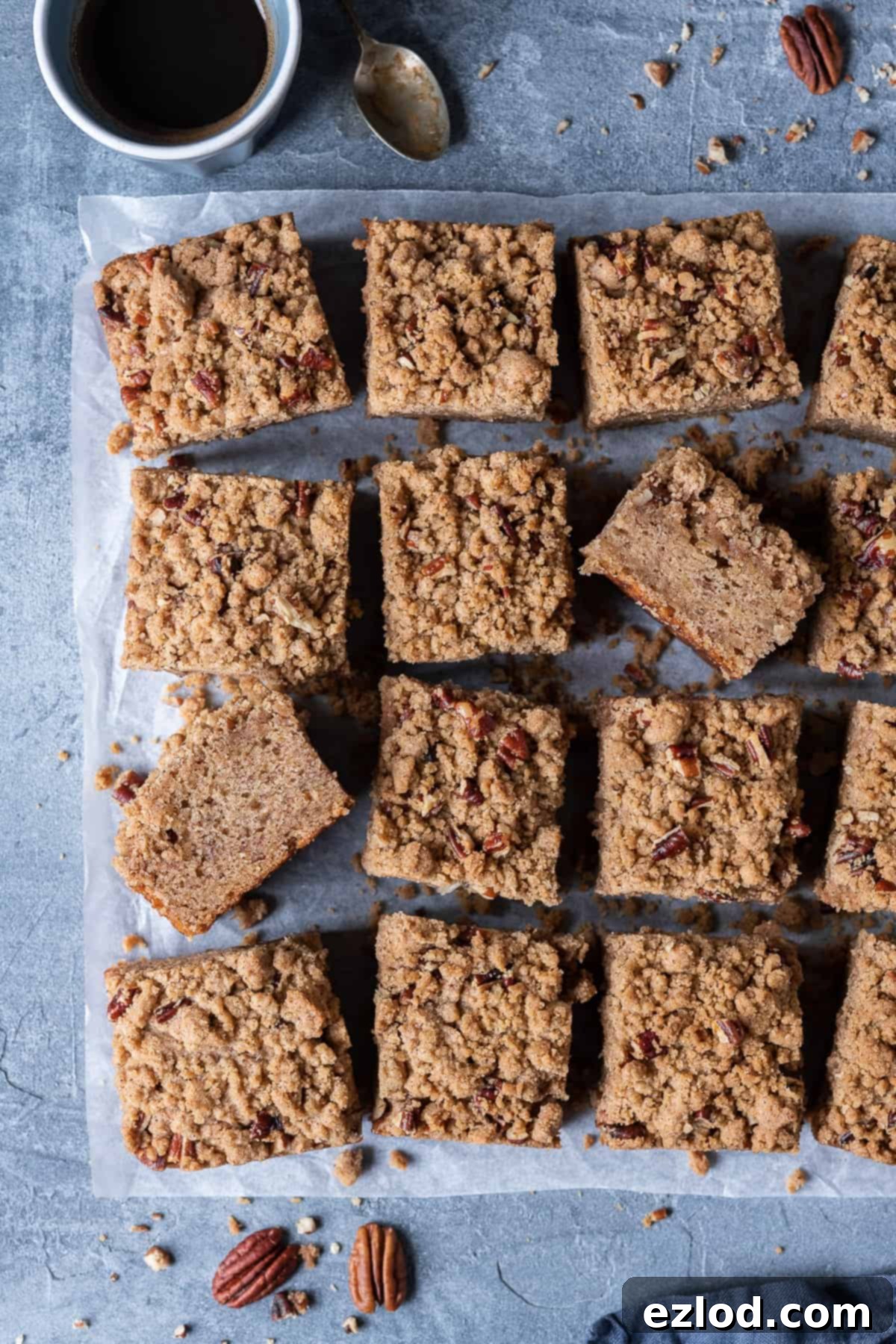 Banana crumb cake on a sheet of baking parchment on a grey background with a cup of espresso.