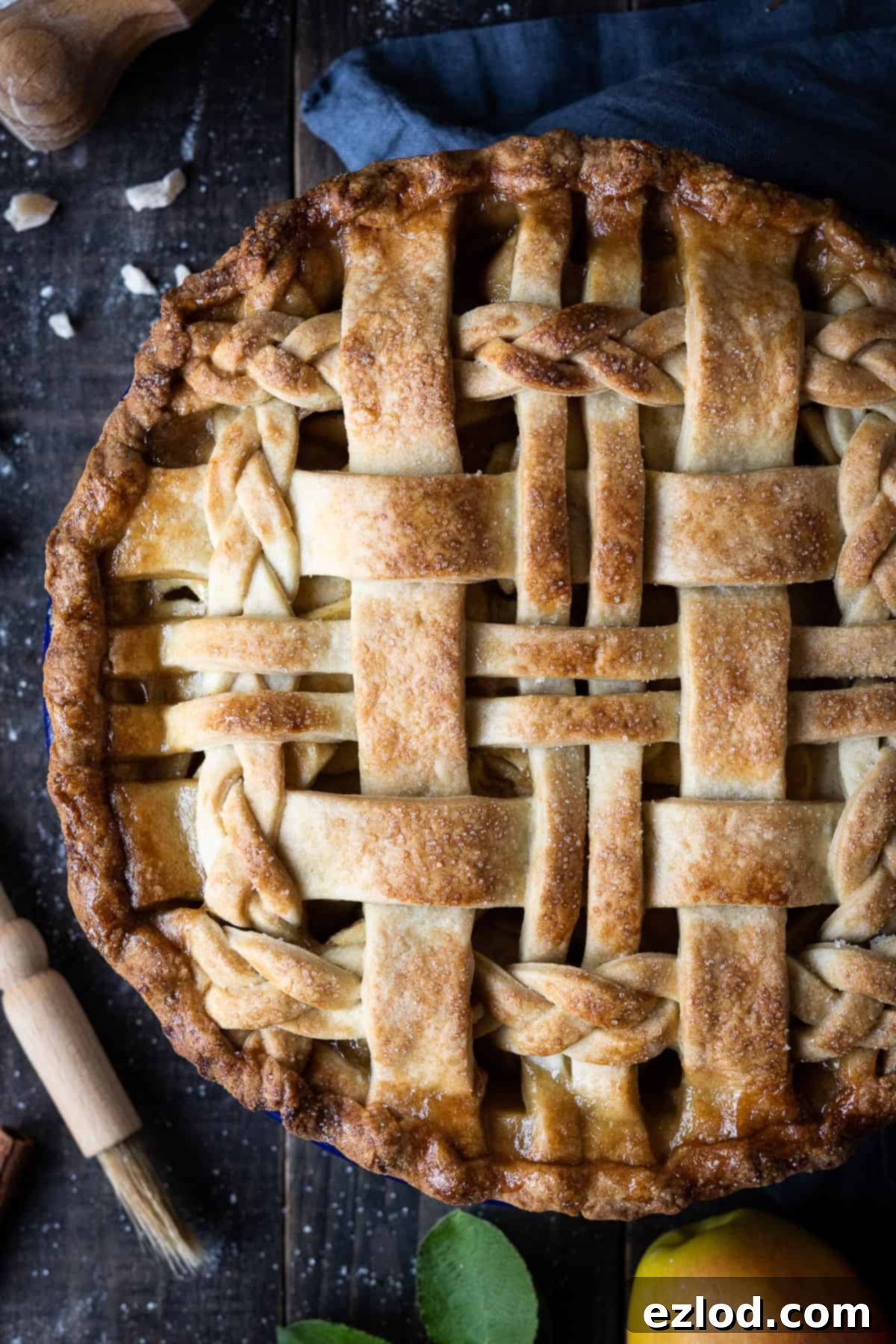 A close-up view of the intricate lattice crust on top of a vegan ginger apple pie, showcasing the golden-brown color and texture of the baked pastry.