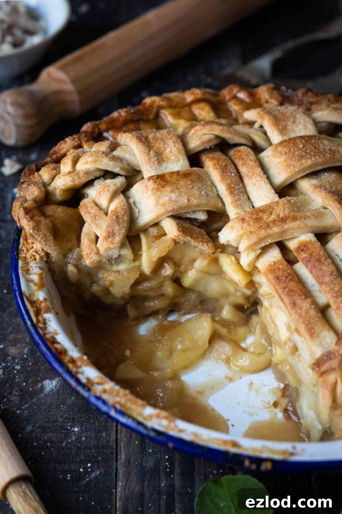 A close-up shot of a sliced vegan ginger apple pie in a charming blue and white enamel pie dish, ready to be served.