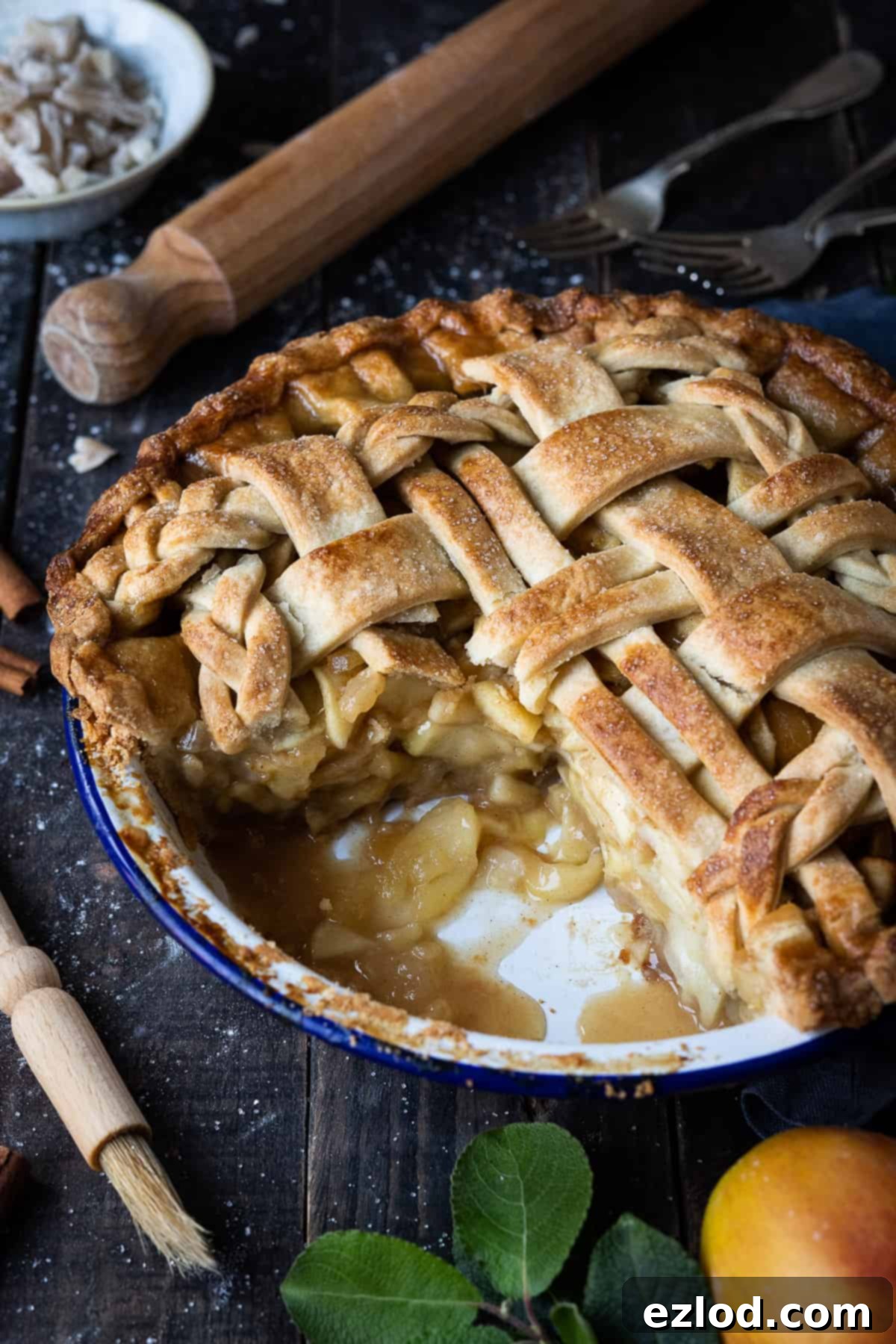 A freshly baked and sliced vegan ginger apple pie resting on a dark wooden surface, showcasing its delicious apple and ginger filling and golden crust.