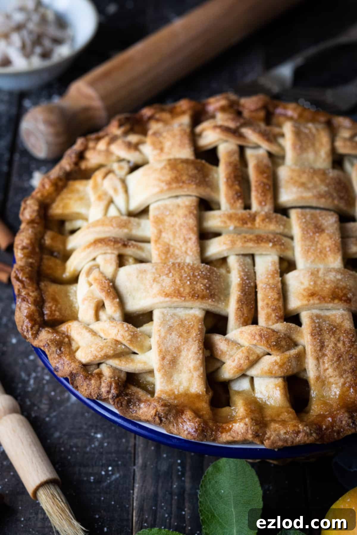 A close-up shot of a baked vegan ginger apple pie, revealing its intricate lattice top crust and the golden-brown caramelized edges.