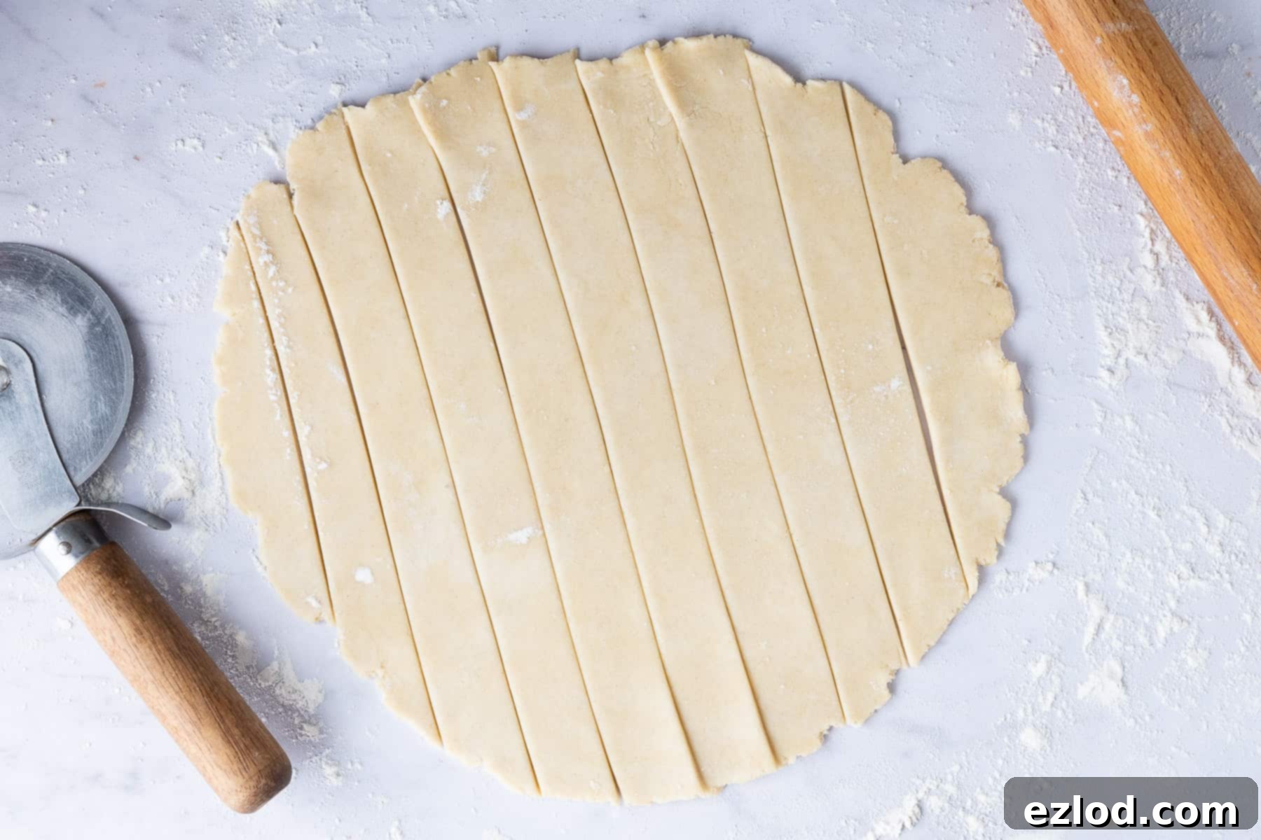 Step-by-step image illustrating the creation of a lattice pie crust, showing pastry being cut into uniform strips using a pizza cutter on a floured surface.