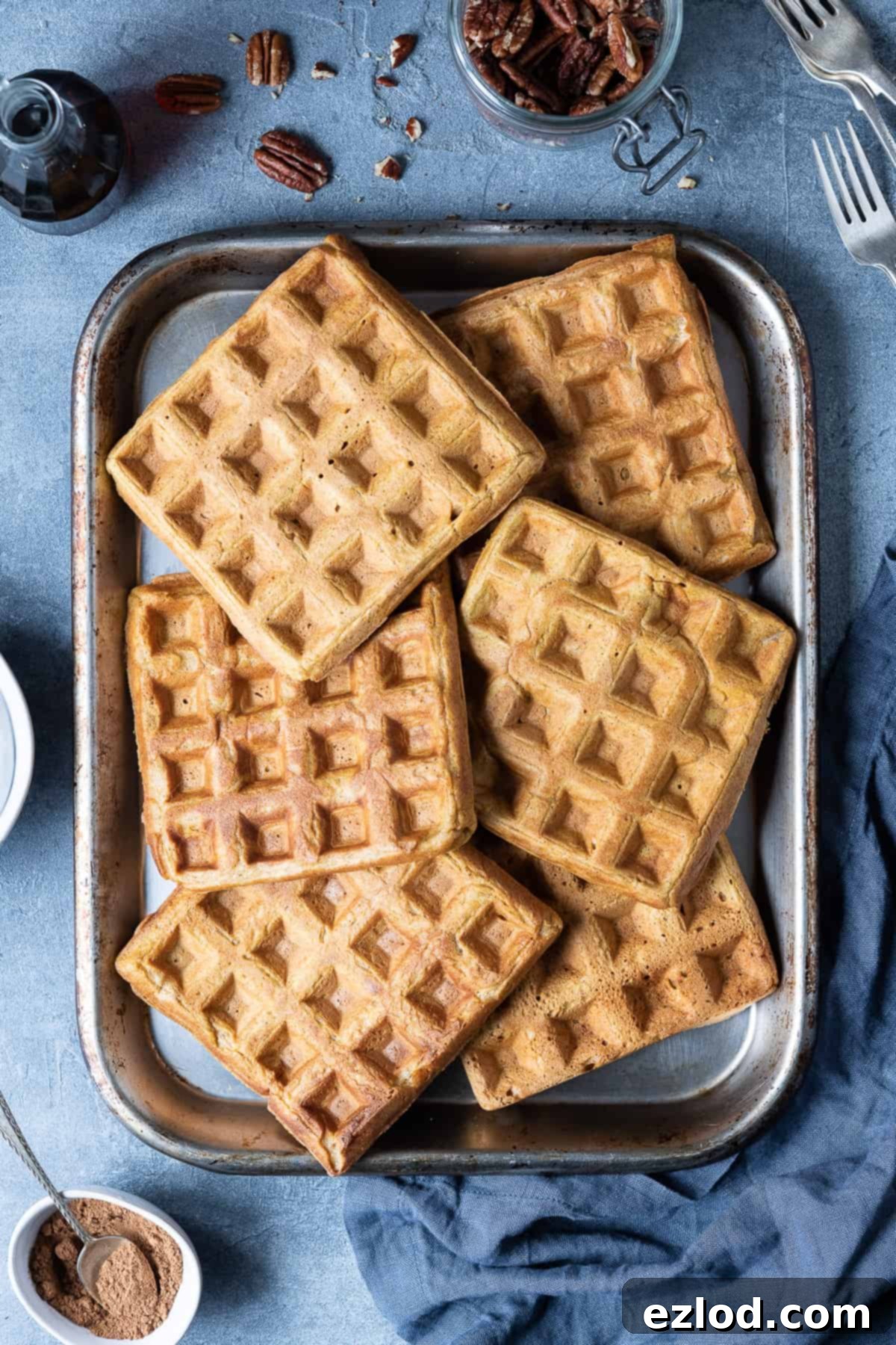 Pumpkin waffles cooling on a metal baking tray on a grey background.