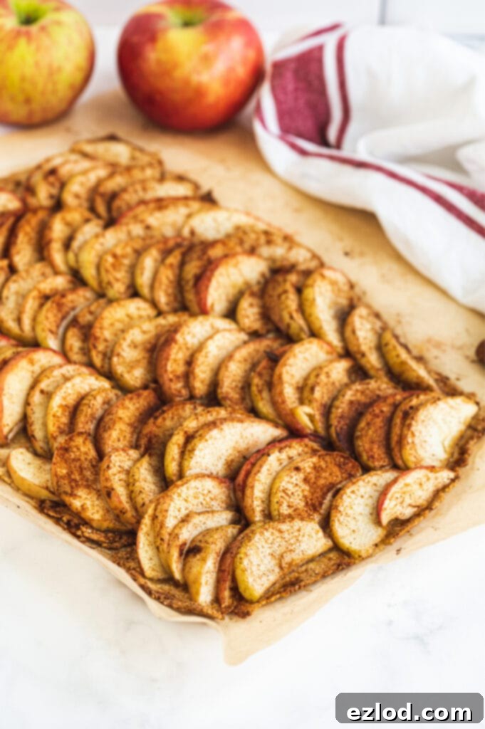 A baking sheet filled with perfectly sliced apples generously topped with cinnamon, resting on a rustic Gluten-Free crust, ready to be baked to golden perfection.