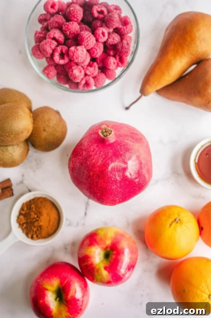 Several fruits including a pomegranate, raspberries and oranges are placed on a white marble surface.
