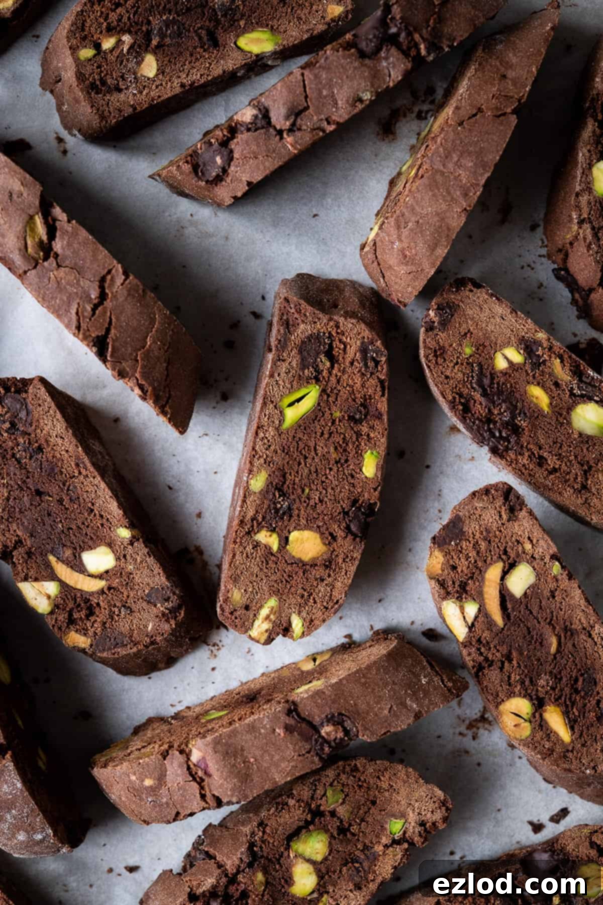 Vegan chocolate pistachio biscotti on a sheet of white baking parchment, showcasing their inviting texture.