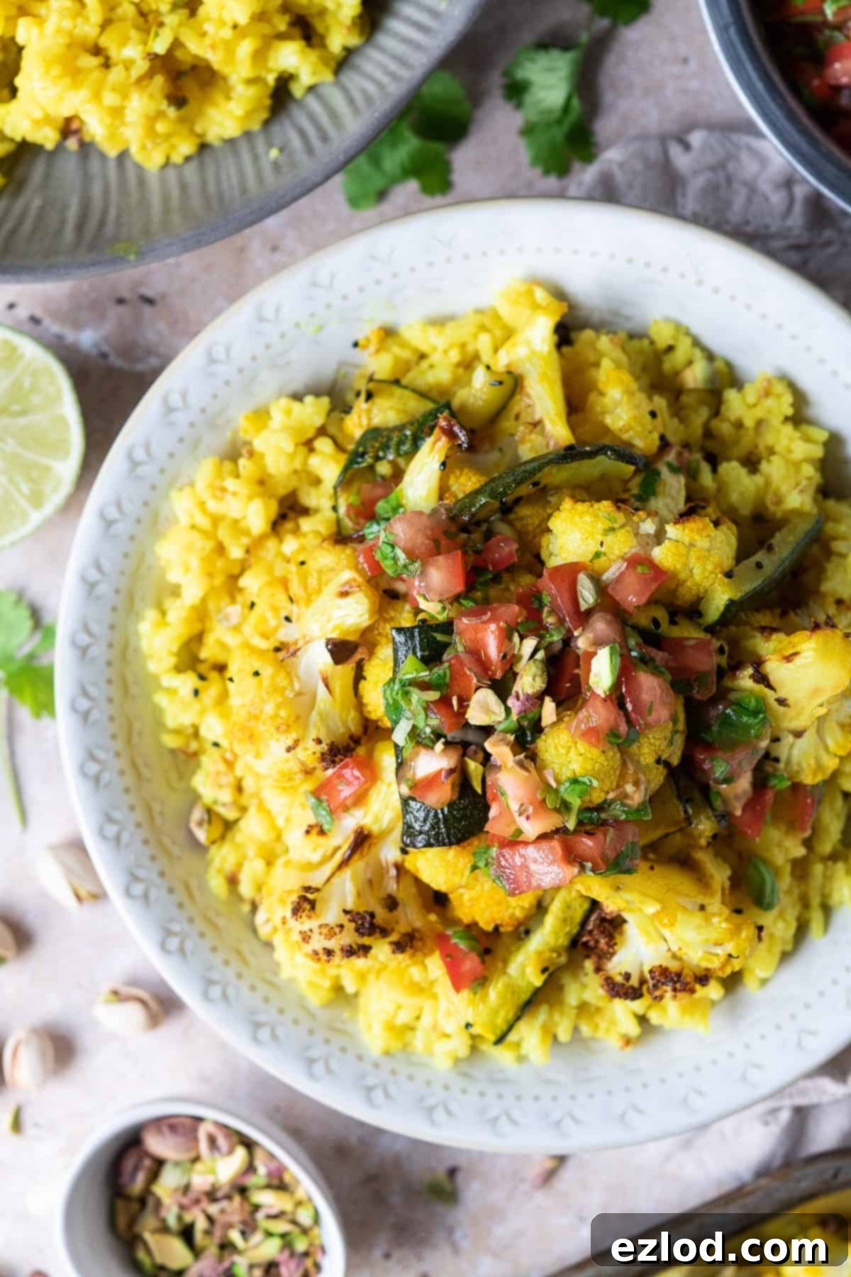 A close-up shot of a white bowl brimming with fluffy yellow rice, generously topped with spiced roasted vegetables and a fresh, vibrant tomato lime salsa, ready to be enjoyed.