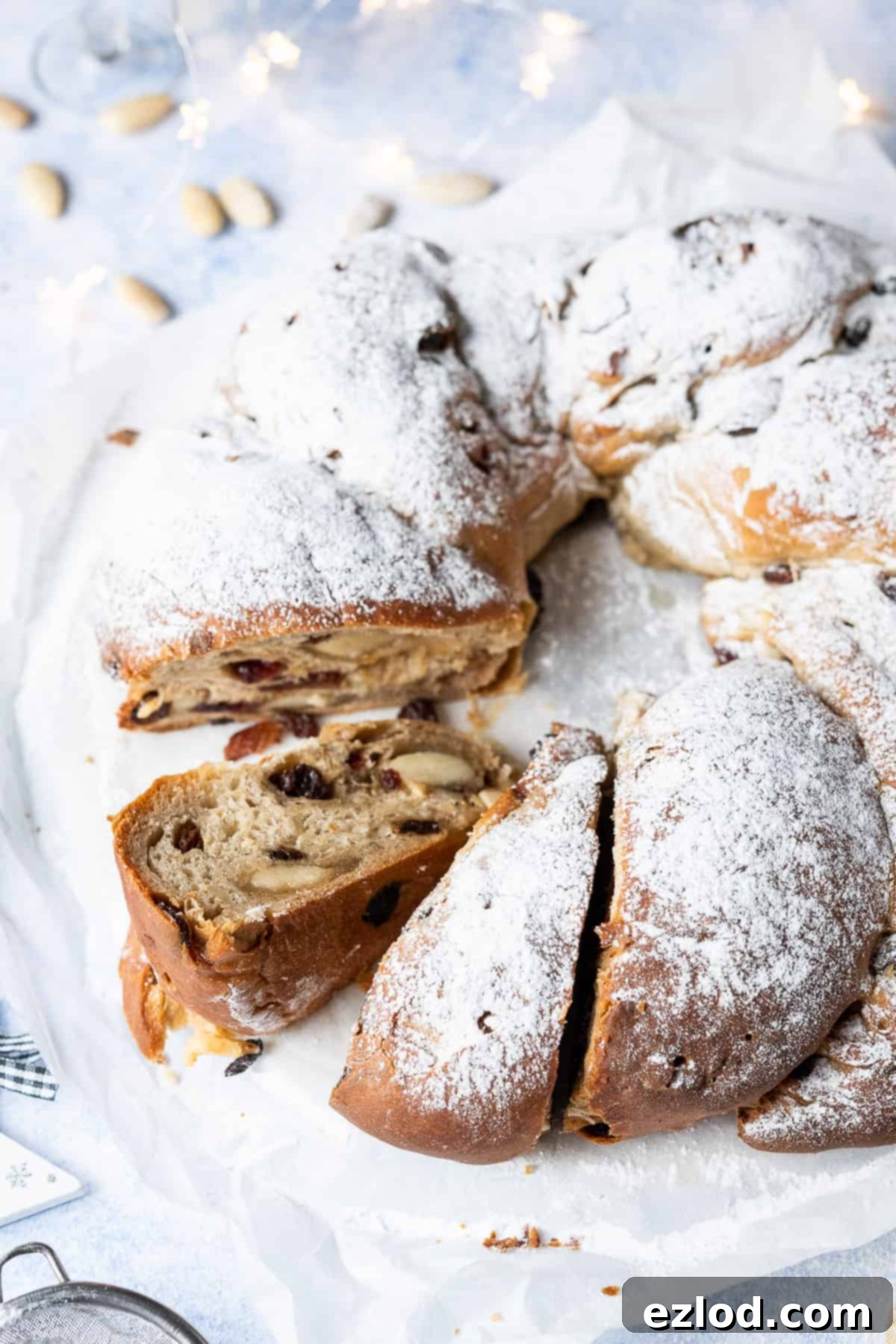 Close up of sliced vegan stollen on white baking parchment with christmas lights in the background.