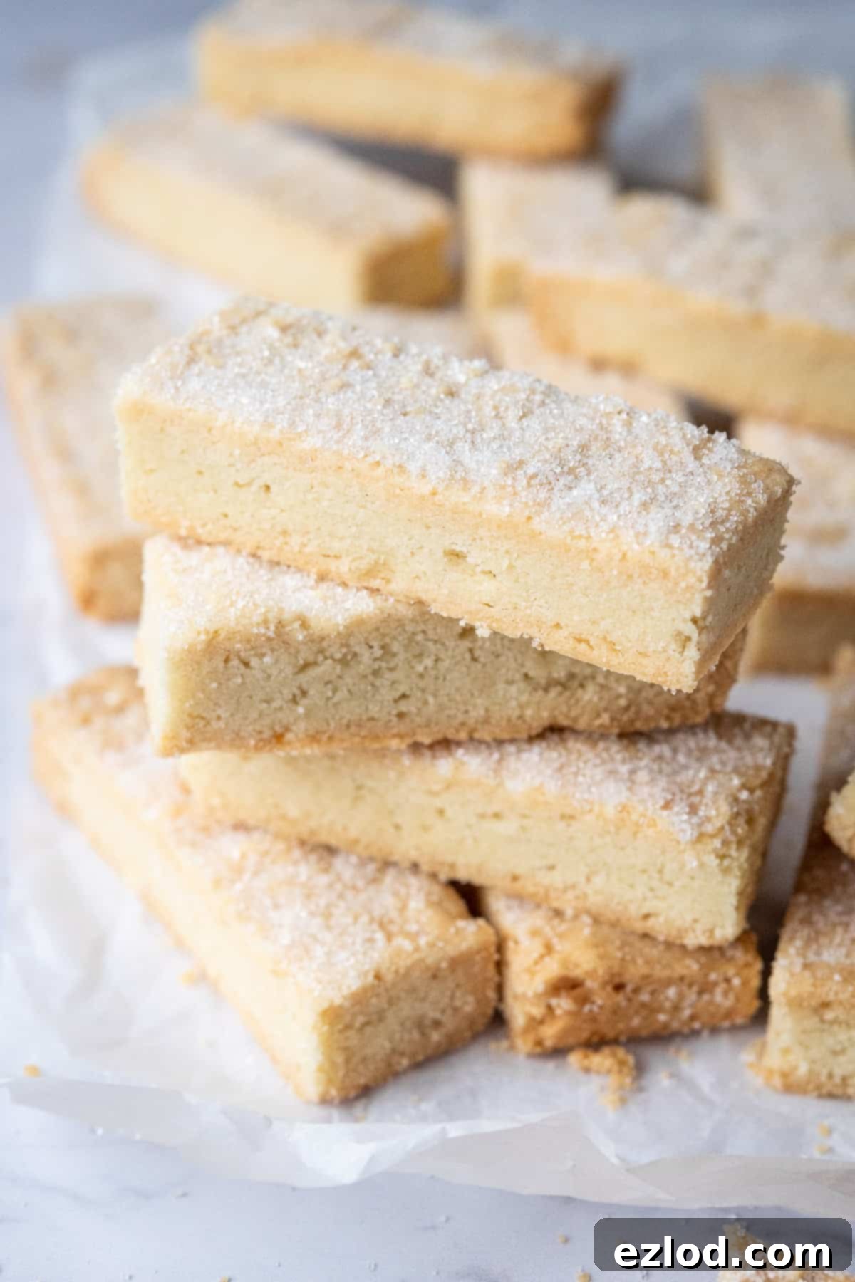A perfectly arranged stack of golden vegan shortbread fingers, highlighting their inviting texture and uniform shape.