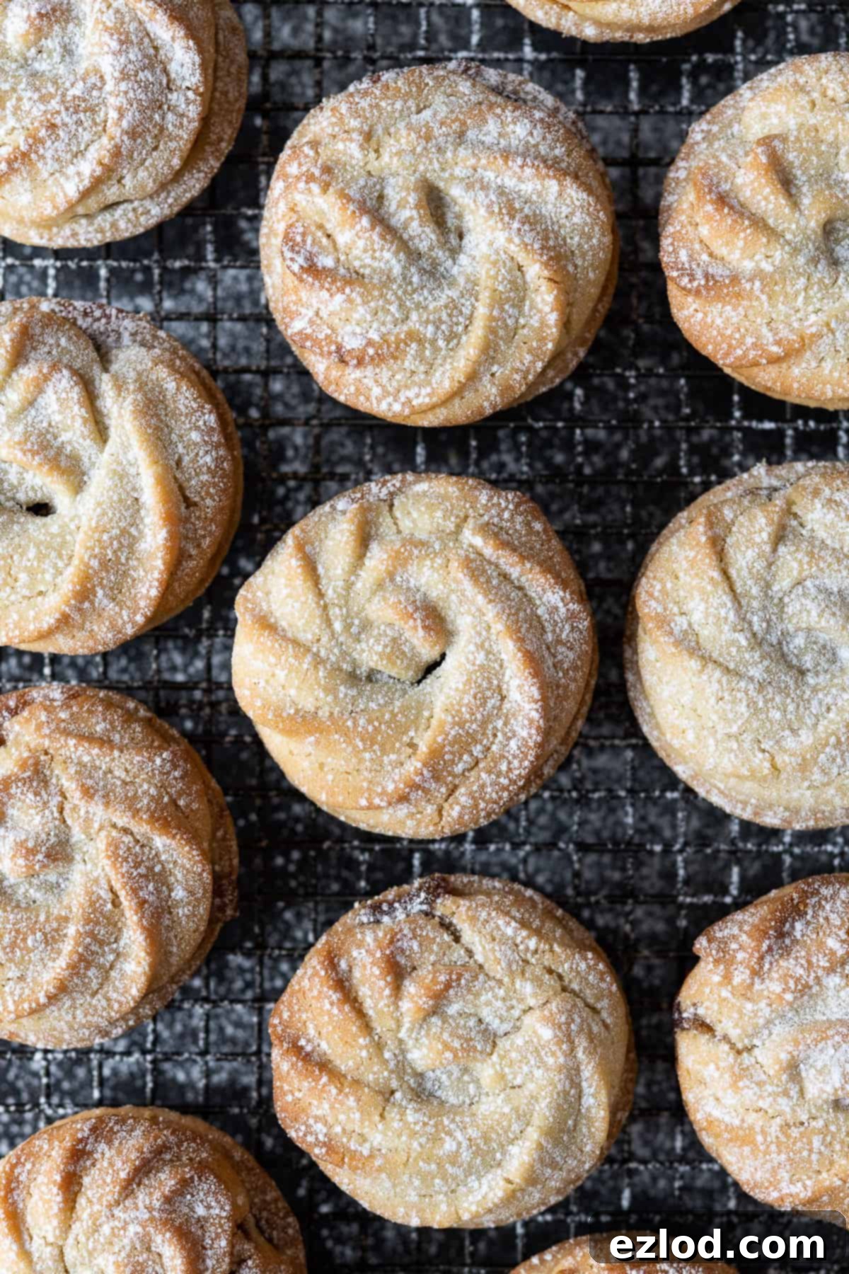 Top down view of freshly baked vegan Viennese whirl mince pies cooling on a metal rack, showcasing their beautifully piped biscuit topping.