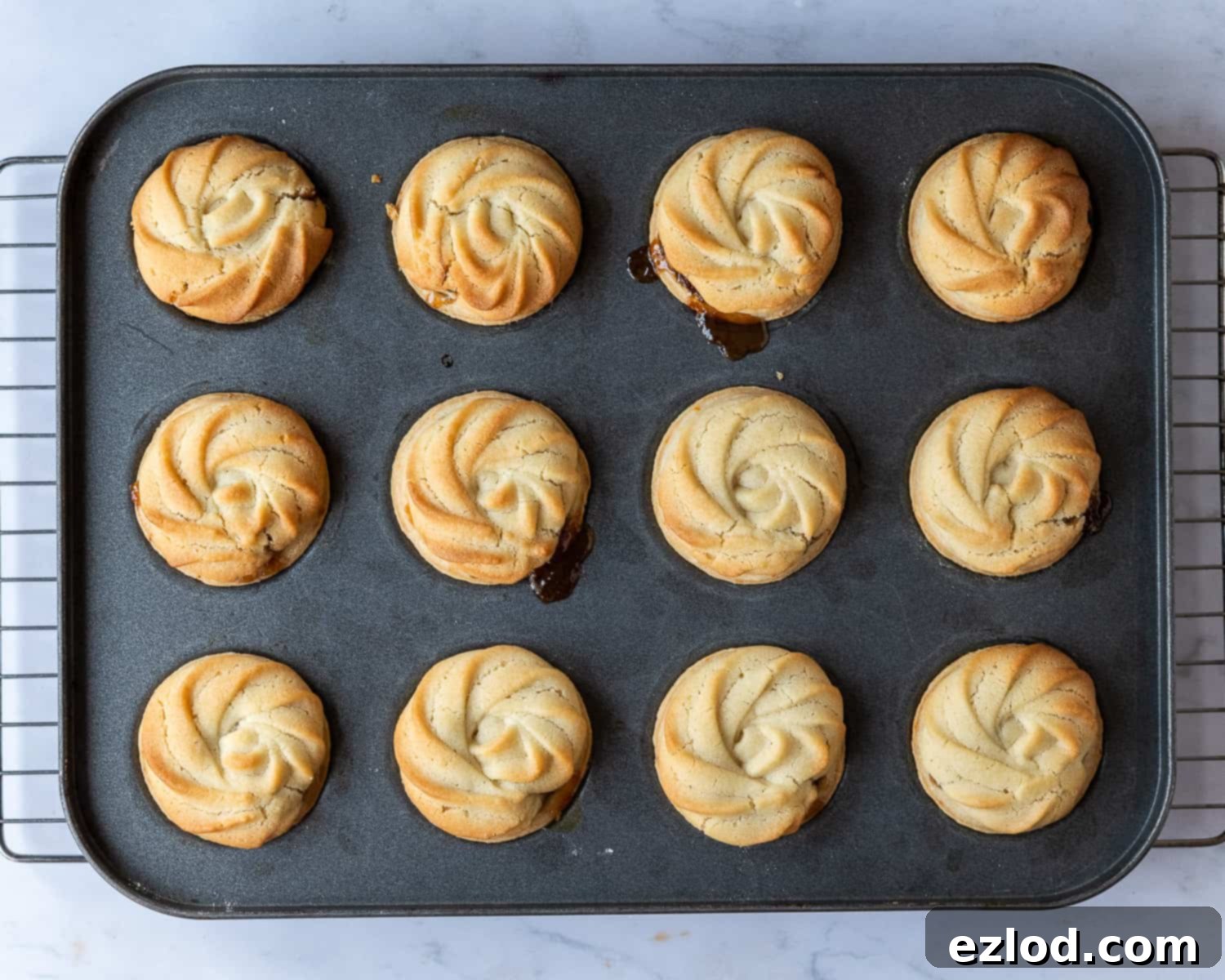 Step-by-step image showing the freshly baked vegan Viennese whirl mince pies cooling in their tin, showcasing their golden-brown finish.