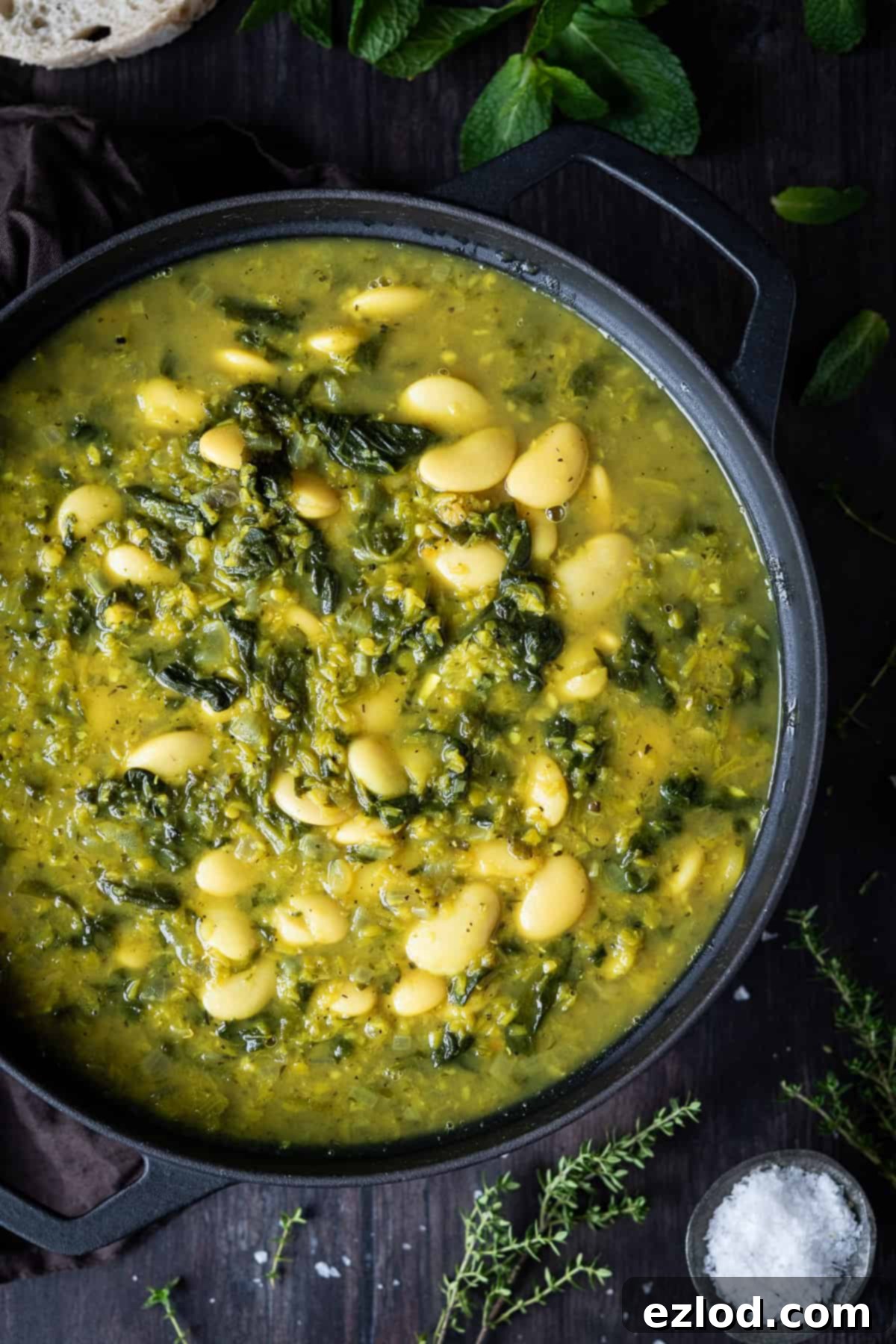 Close up of soup in a black pan on a wooden table.