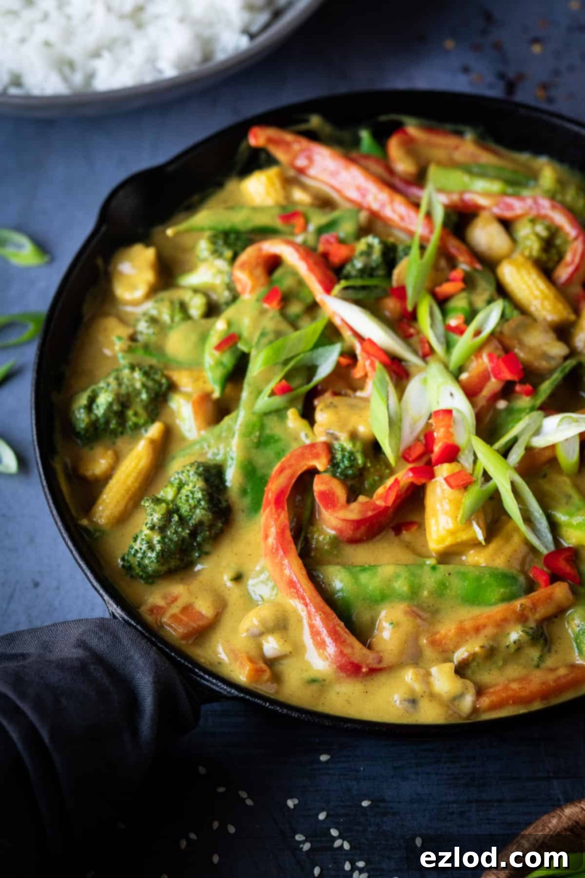 Close-up image of a vibrant Chinese vegetable curry simmering in a black skillet, showcasing the rich texture and appealing colors of the plant-based dish.
