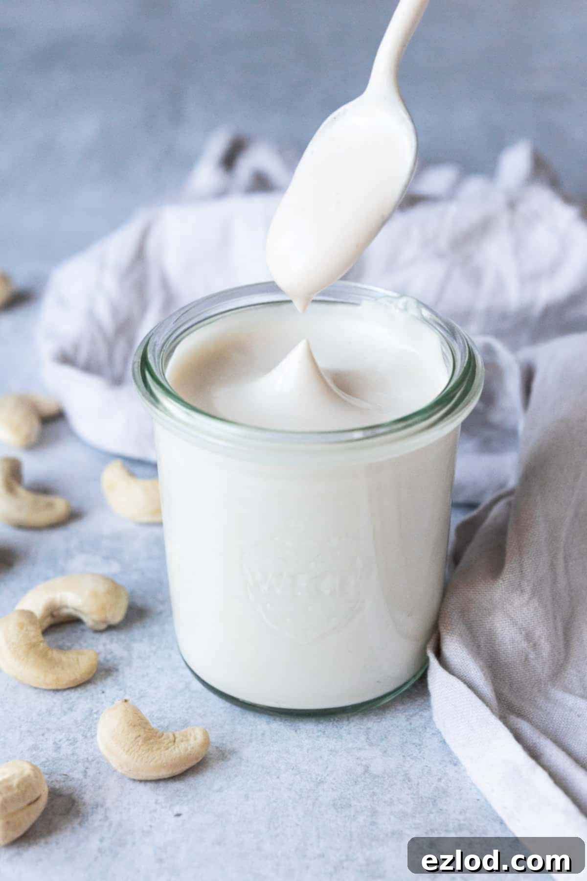 A jar of cashew cream with a spoon being dipped in.