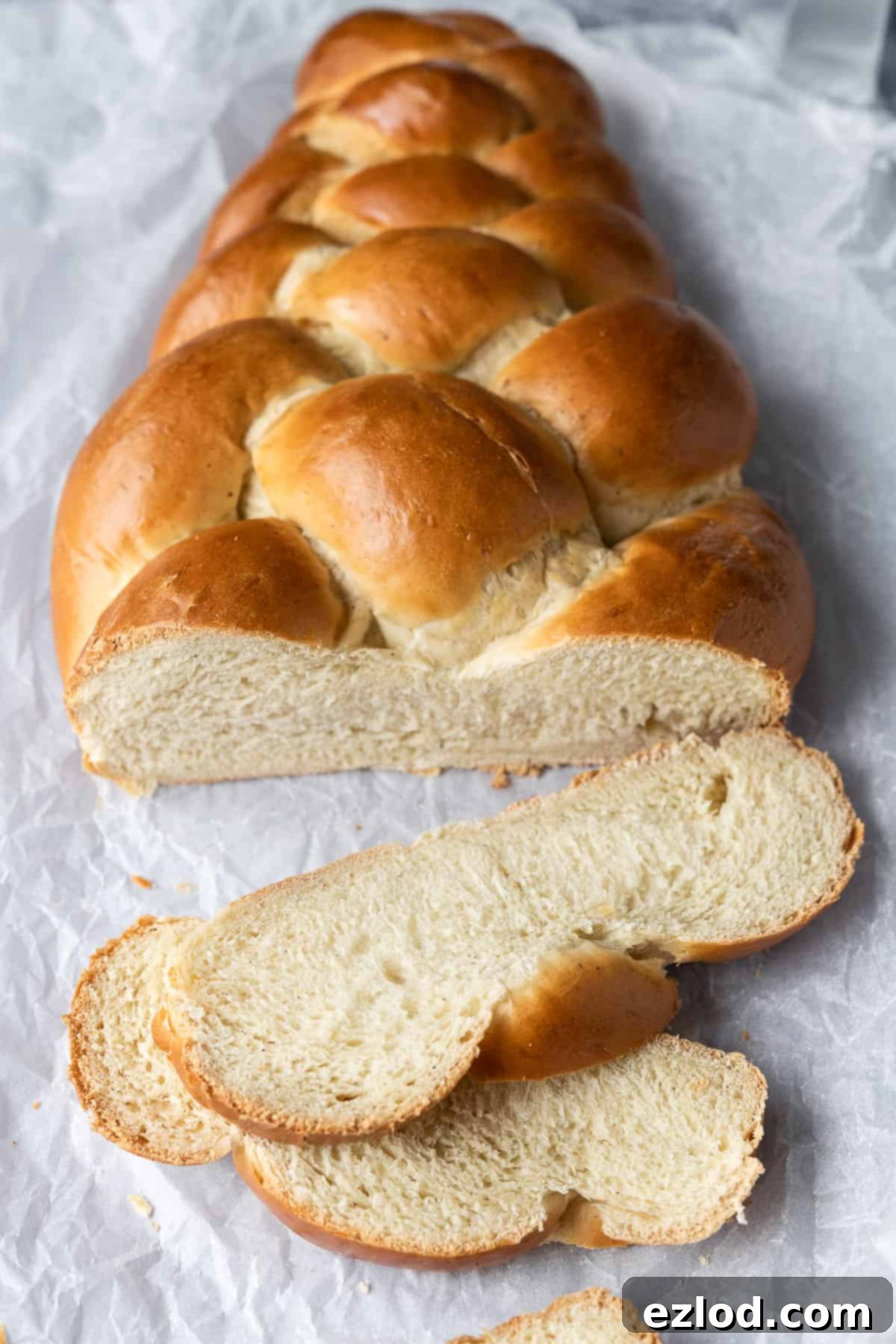 Three perfectly sliced pieces of vegan pulla bread on white baking parchment, showcasing the fluffy interior and inviting aroma.