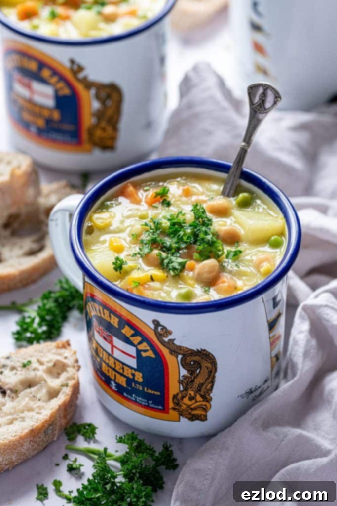 A close-up shot of creamy vegetable chickpea soup served in a charming blue and white enamel mug, ready to be enjoyed.