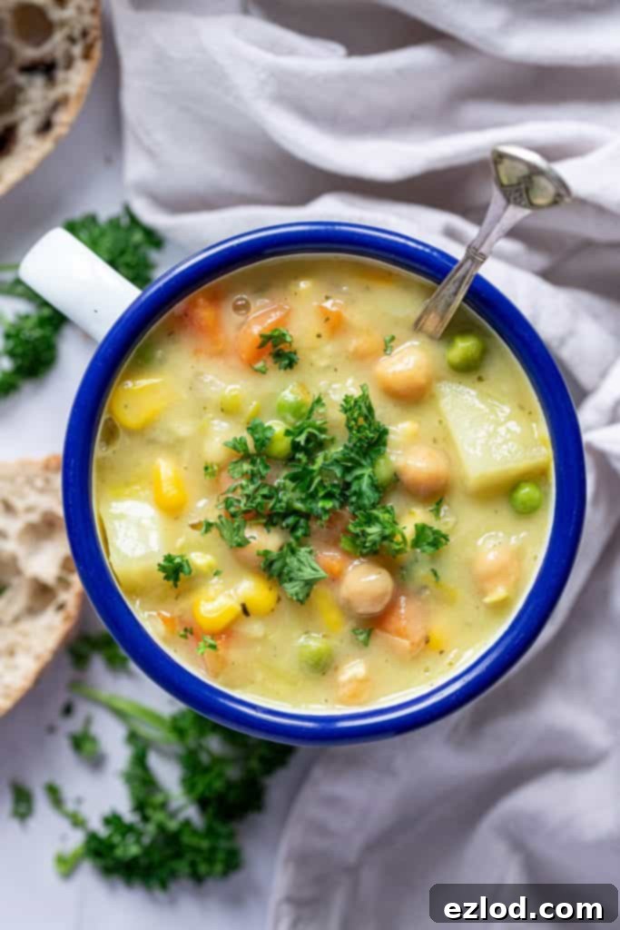 A charming close-up of creamy vegetable chickpea soup served in a blue and white enamel mug, showcasing its texture and ready to be enjoyed.