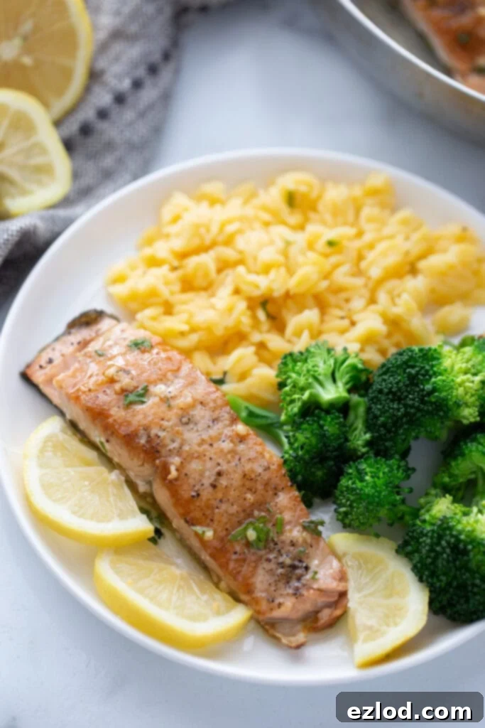 High angle photo of a crispy salmon fillet on a white plate with broccoli and gluten free orzo, highlighting the golden-brown crust.