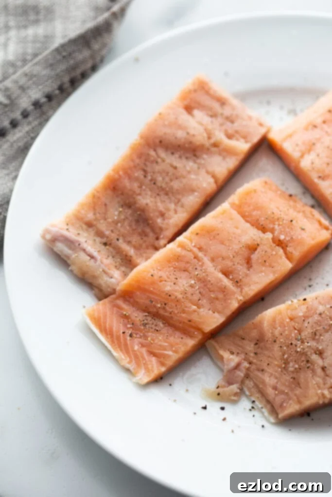 Raw salmon fillets seasoned with salt and pepper, ready for searing.
