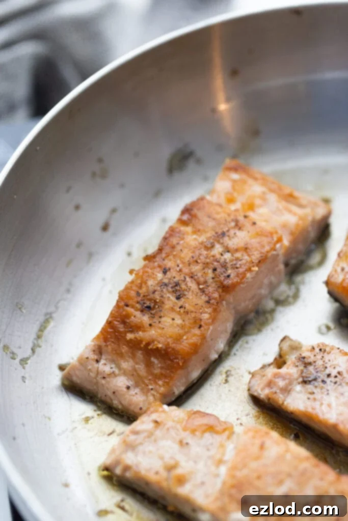 Crispy salmon fillets cooked stovetop in a pan, ready for sauce.