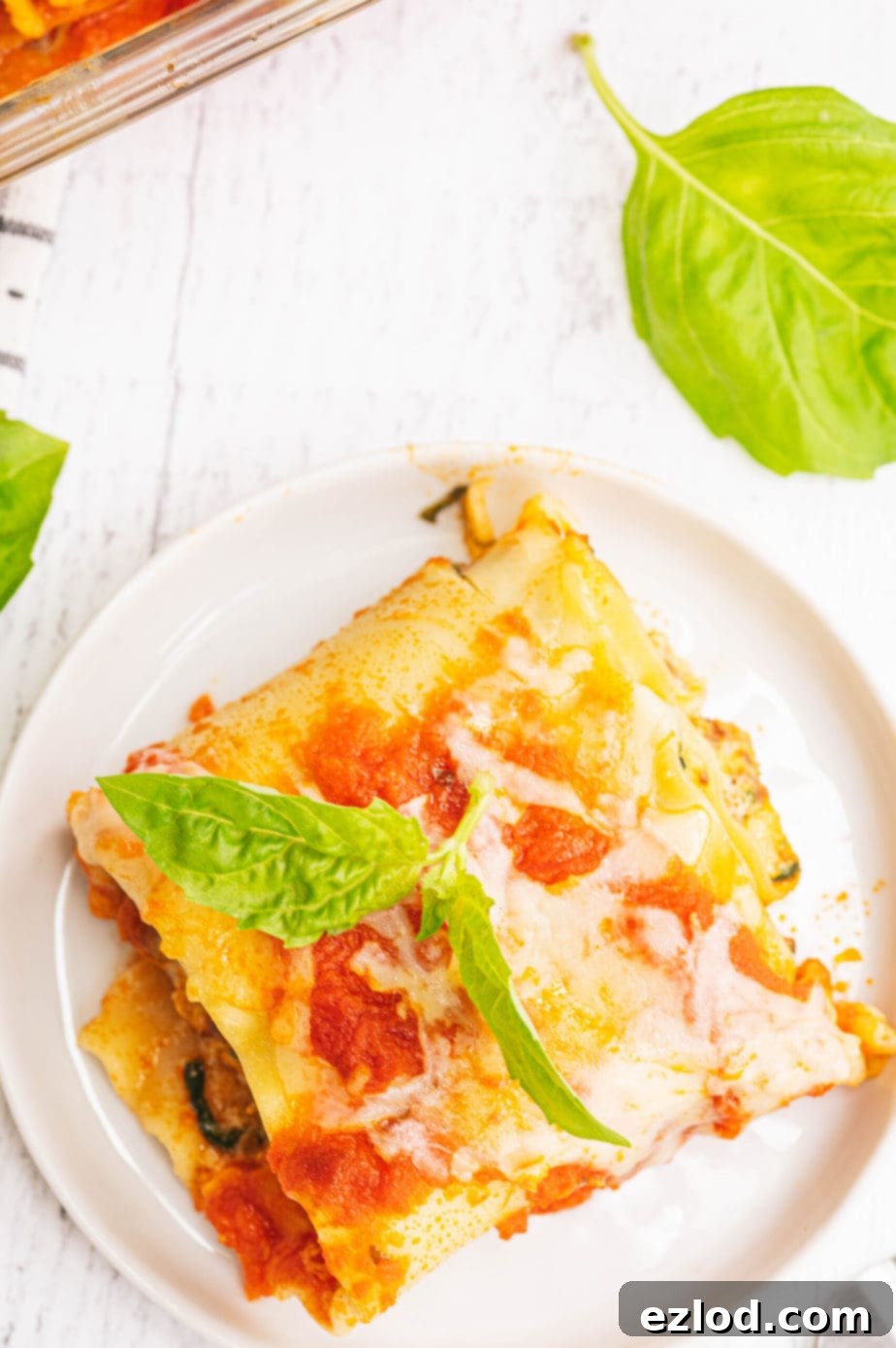 A single perfectly rolled lasagna roll-up on a white plate, showcasing its golden-brown top and rich filling.