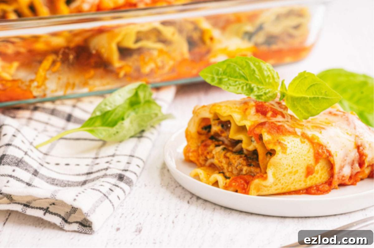 Side view of a partially assembled lasagna roll-up in a baking dish, showing the creamy spinach and sausage filling.