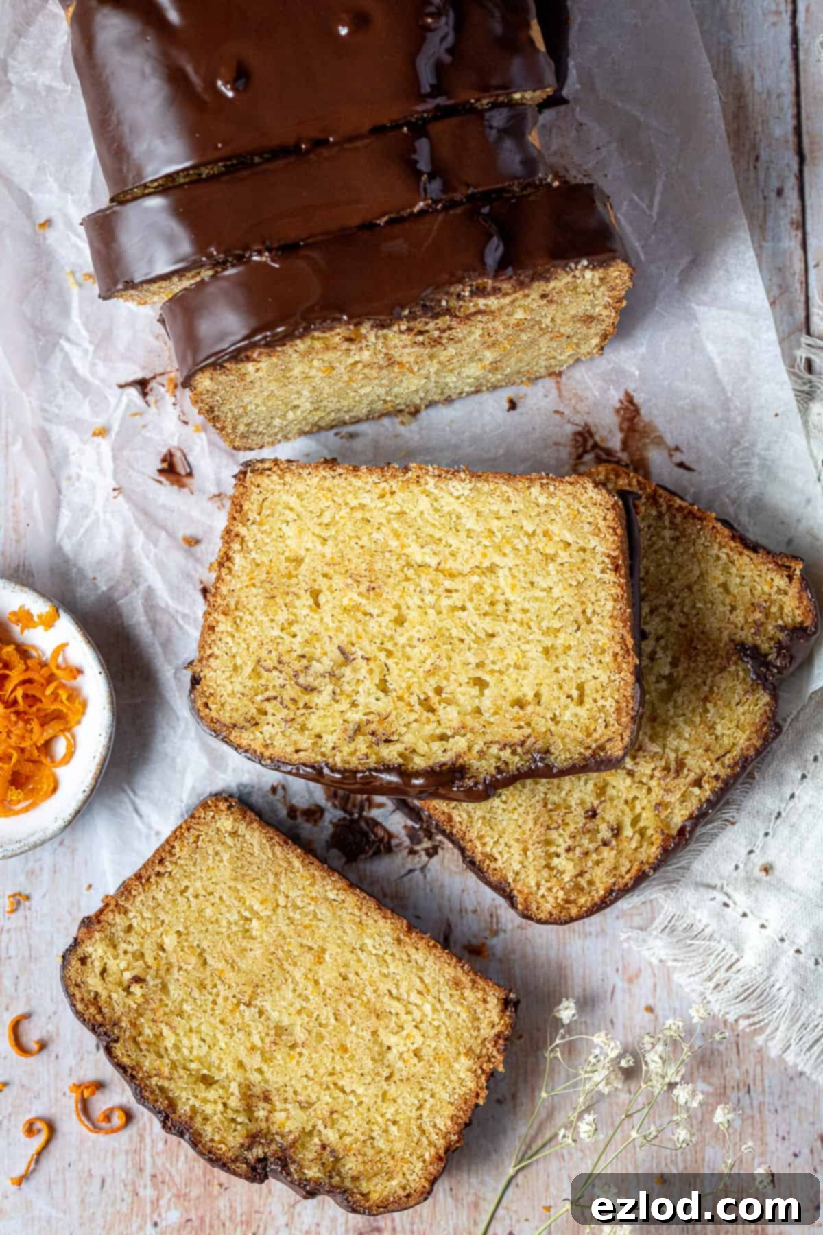 Neatly arranged slices of vegan orange loaf cake resting on a sheet of baking parchment, ready to be enjoyed.