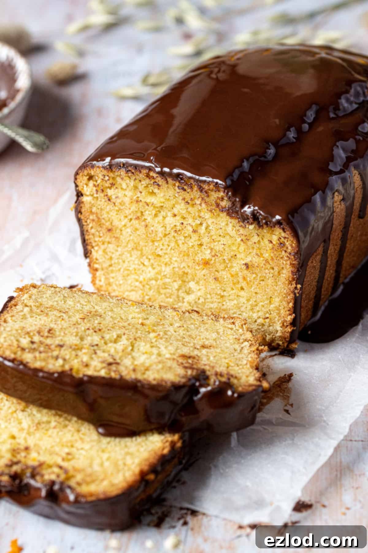Close up of a freshly baked vegan orange loaf cake with melted chocolate glaze and orange zest, perfectly sliced and ready to be served.