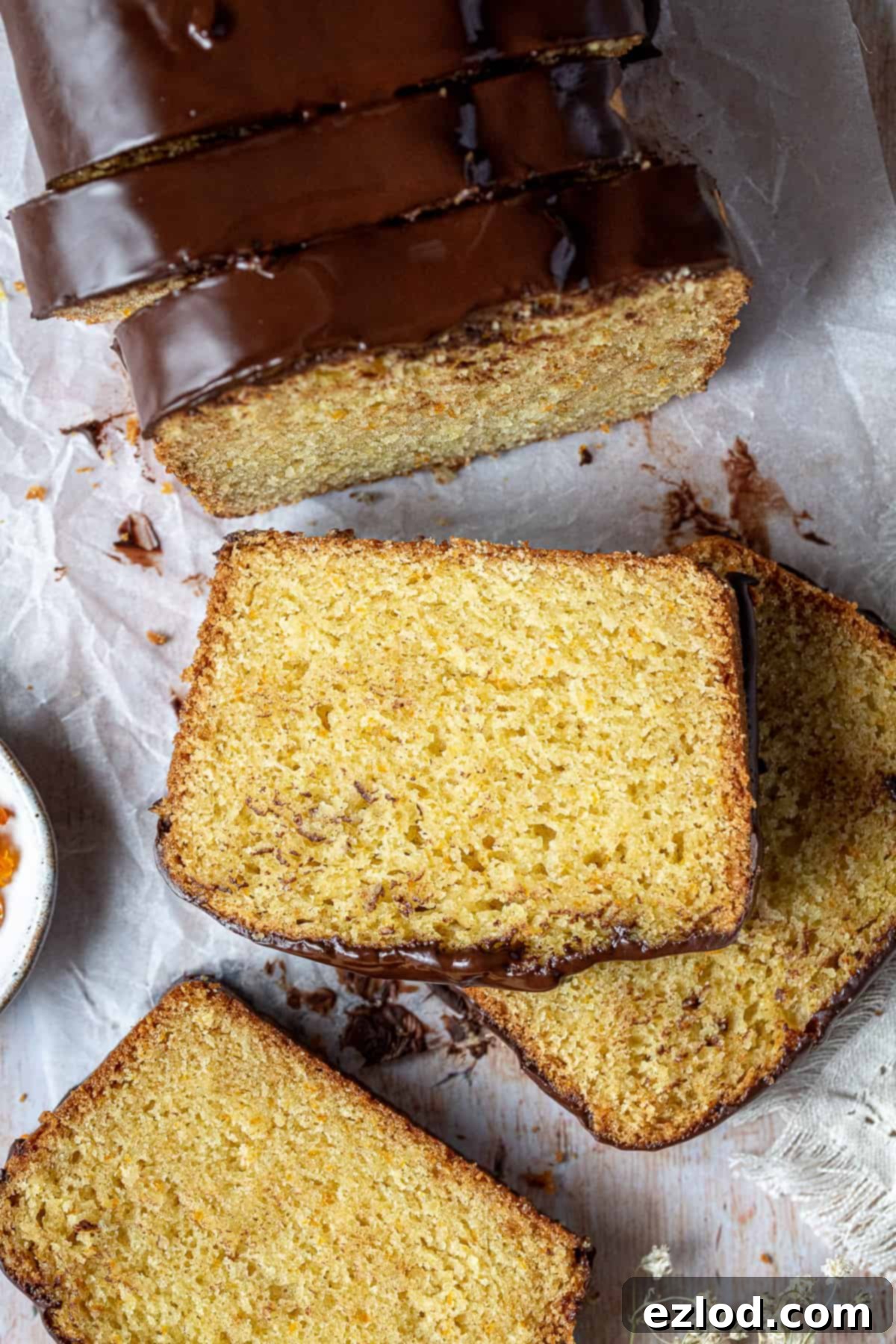 A tantalizing close-up of a single slice of vegan orange loaf cake, showcasing its vibrant orange color and moist texture.
