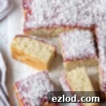 Slices of vegan jam and coconut sponge cake on a sheet of baking parchment.
