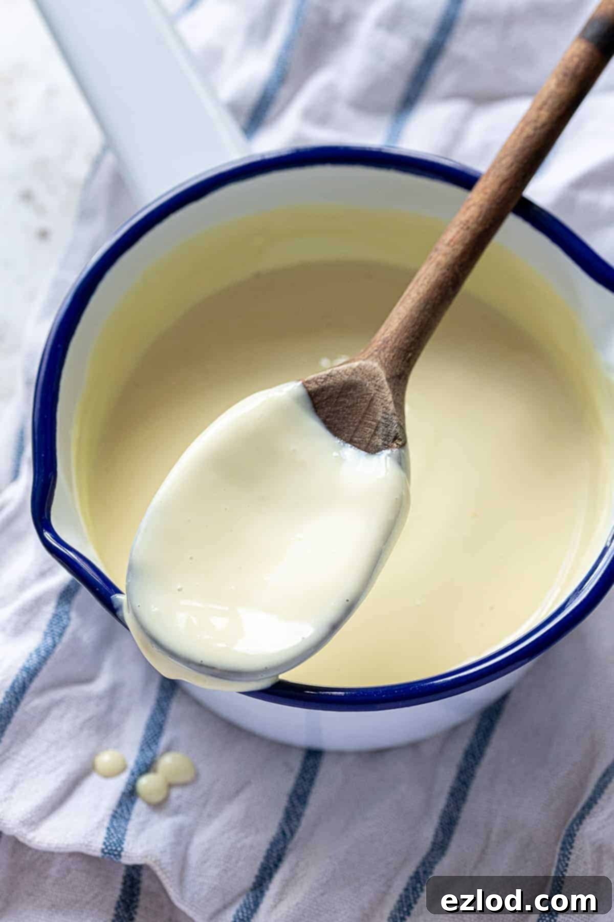Close-up view of a wooden spoon generously coated with smooth, creamy vegan vanilla custard.