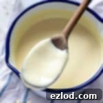 A bowl of creamy vegan custard with a spoon, ready to be enjoyed.