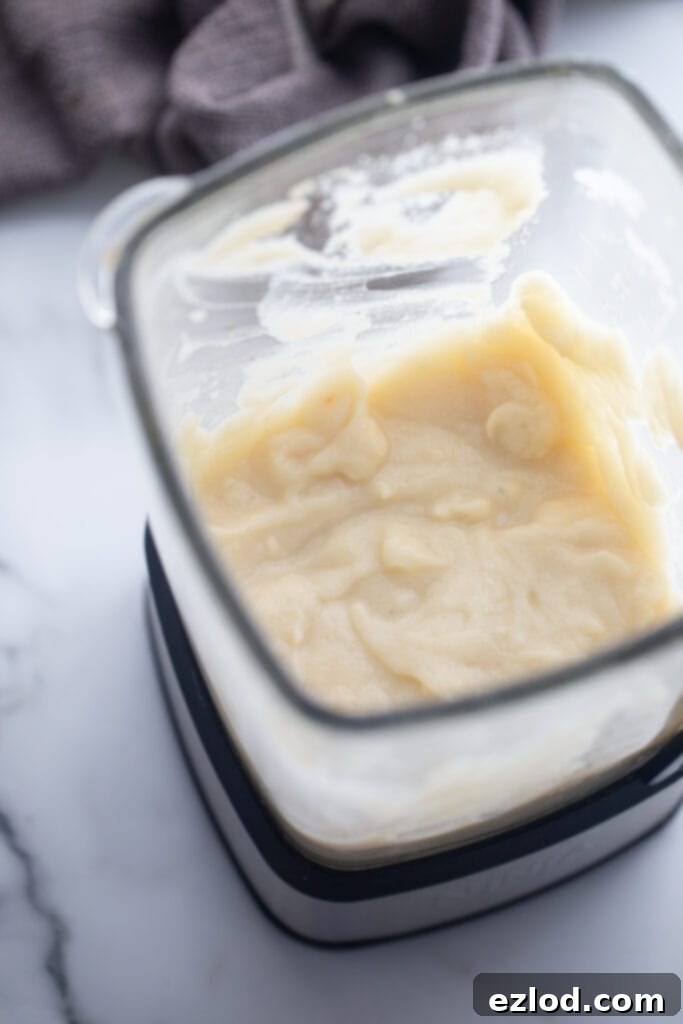 A blender filled with the creamy, blended cauliflower mixture, ready to be incorporated back into the chicken pot pie soup.