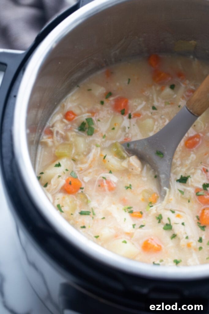 A large pot full of steaming, healthy Instant Pot chicken pot pie soup, ready to be served, showcasing its rich, creamy texture and hearty ingredients.