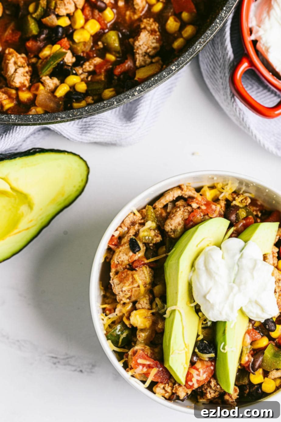 overhead image: a bowl of taco skillet topped with two slices of avocado, some shredded cheddar cheese and a dollop of greeyk yogurt, showcasing a perfect serving.