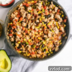 A beautifully presented bowl of the finished Easy Taco Skillet recipe, garnished with vibrant avocado slices, a dollop of creamy Greek yogurt, and a sprinkle of shredded cheese.