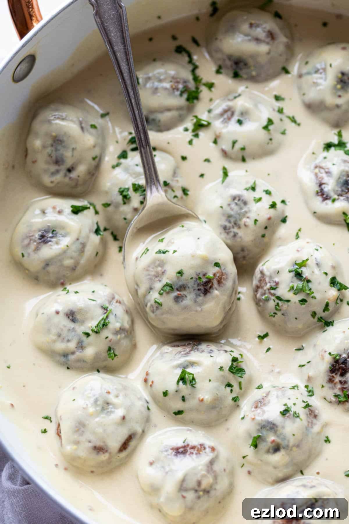 Meatballs in cream sauce with a spoon.