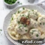 Vegan Swedish meatballs and mashed potato on a white plate with a bowl of parsley and a bowl of mustard.