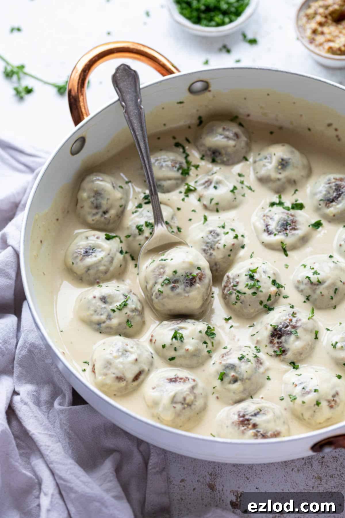 Vegan Swedish meatballs in a white pan with a spoon.