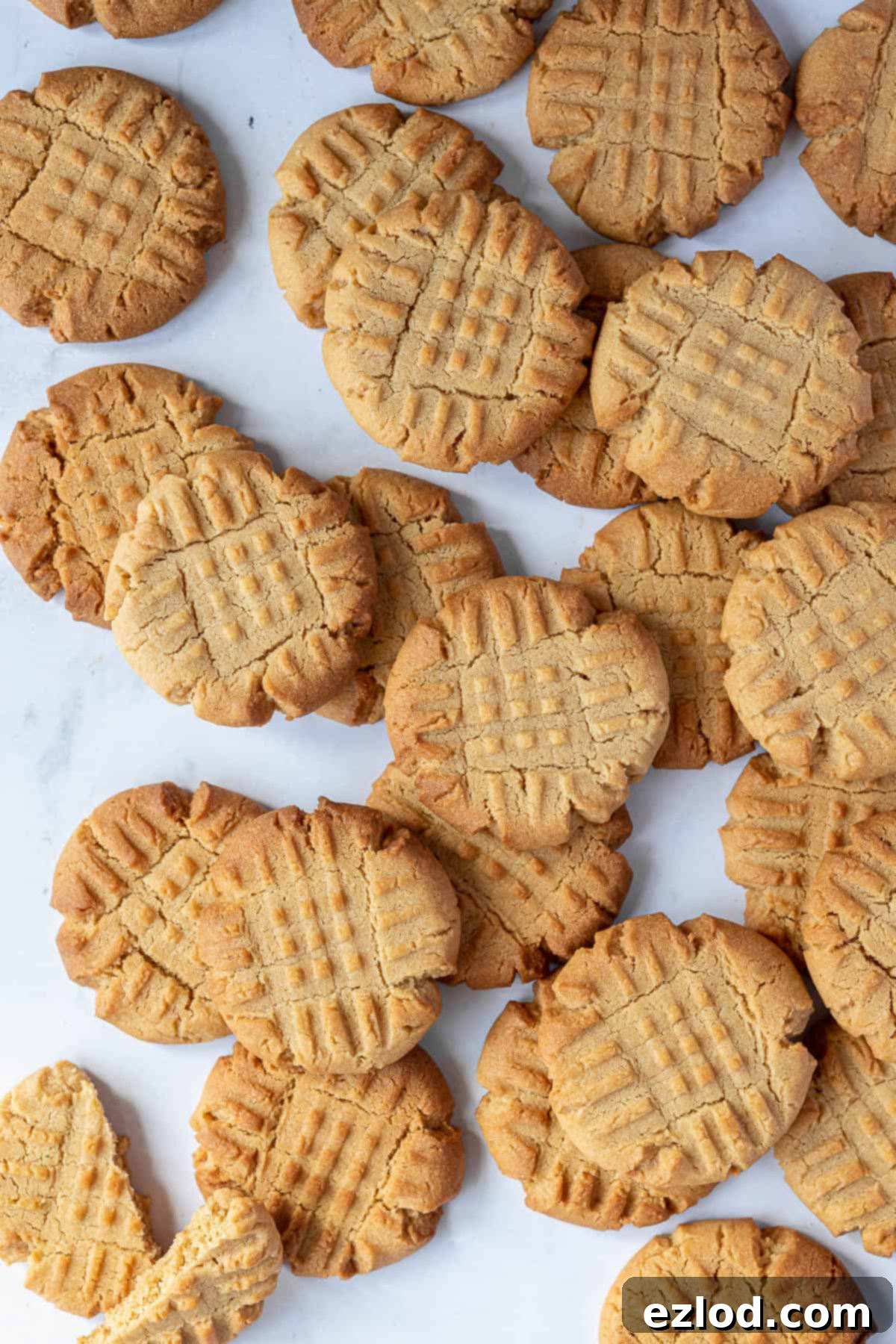 Freshly baked vegan peanut butter cookies stacked on a marble surface, highlighting their golden-brown edges and soft centers.