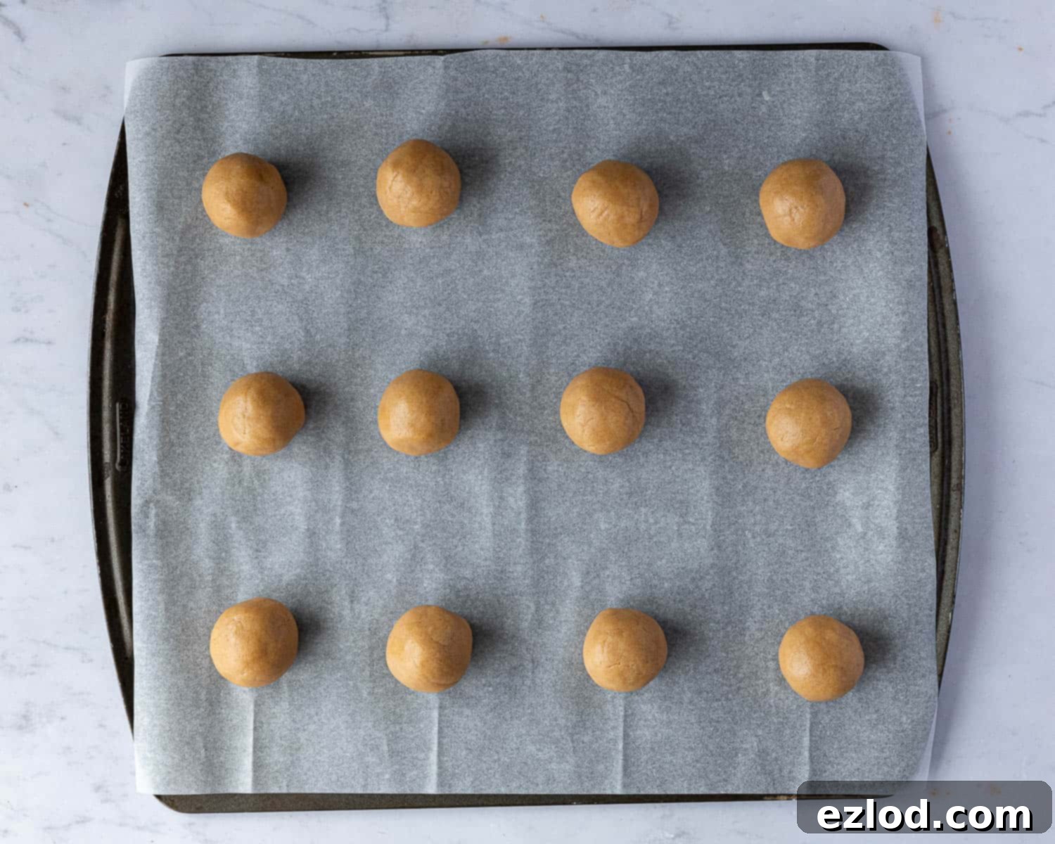 Perfectly shaped vegan peanut butter cookie dough balls arranged on a baking sheet, ready for the oven.