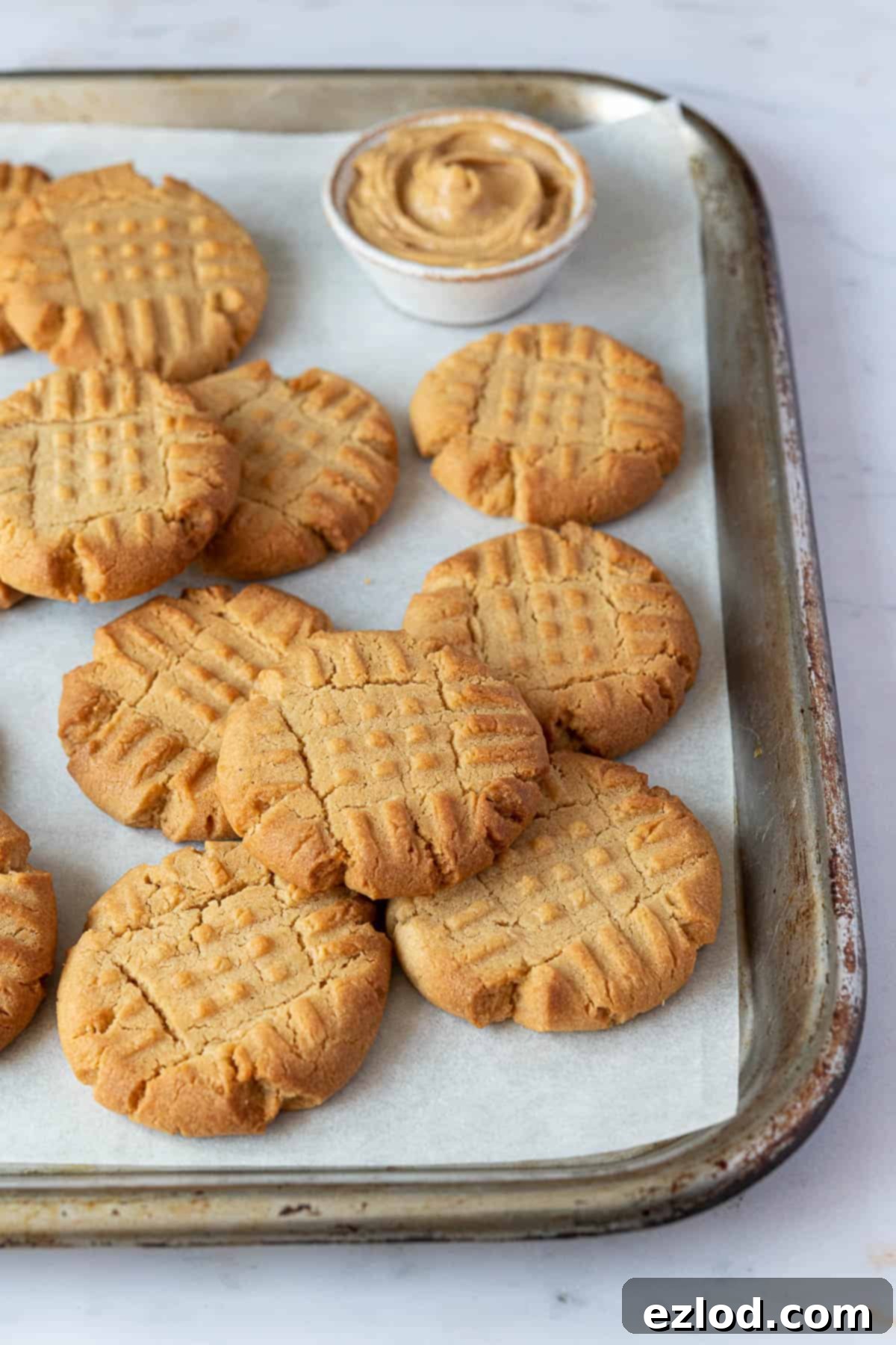 A warm batch of vegan peanut butter cookies cooling on a metal wire rack after baking.