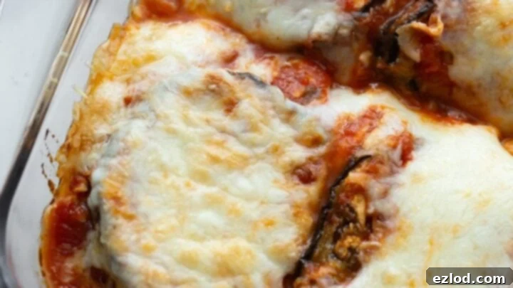 Layers of baked eggplant, marinara, and melted cheese in a healthy Eggplant Parmesan.