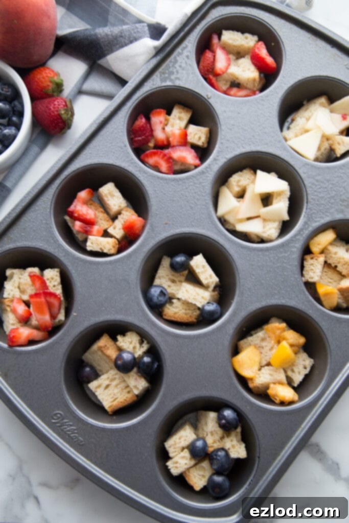 A muffin tin filled with healthy french toast casserole cups topped with various fresh fruit toppings