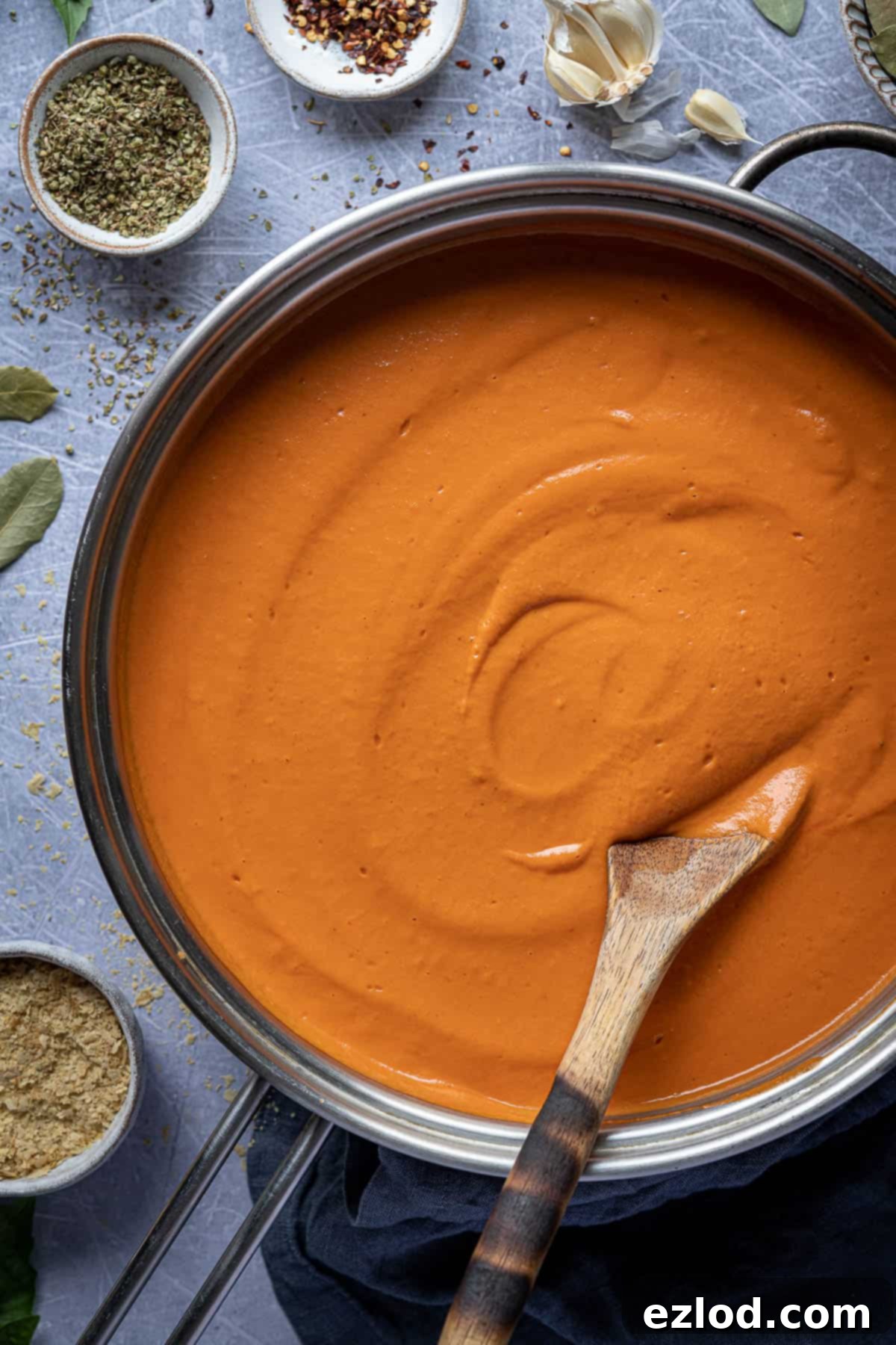 A close-up view of the rich, red, and beautifully creamy tofu tomato pasta sauce simmering gently in a cooking pan, highlighting its smooth texture.