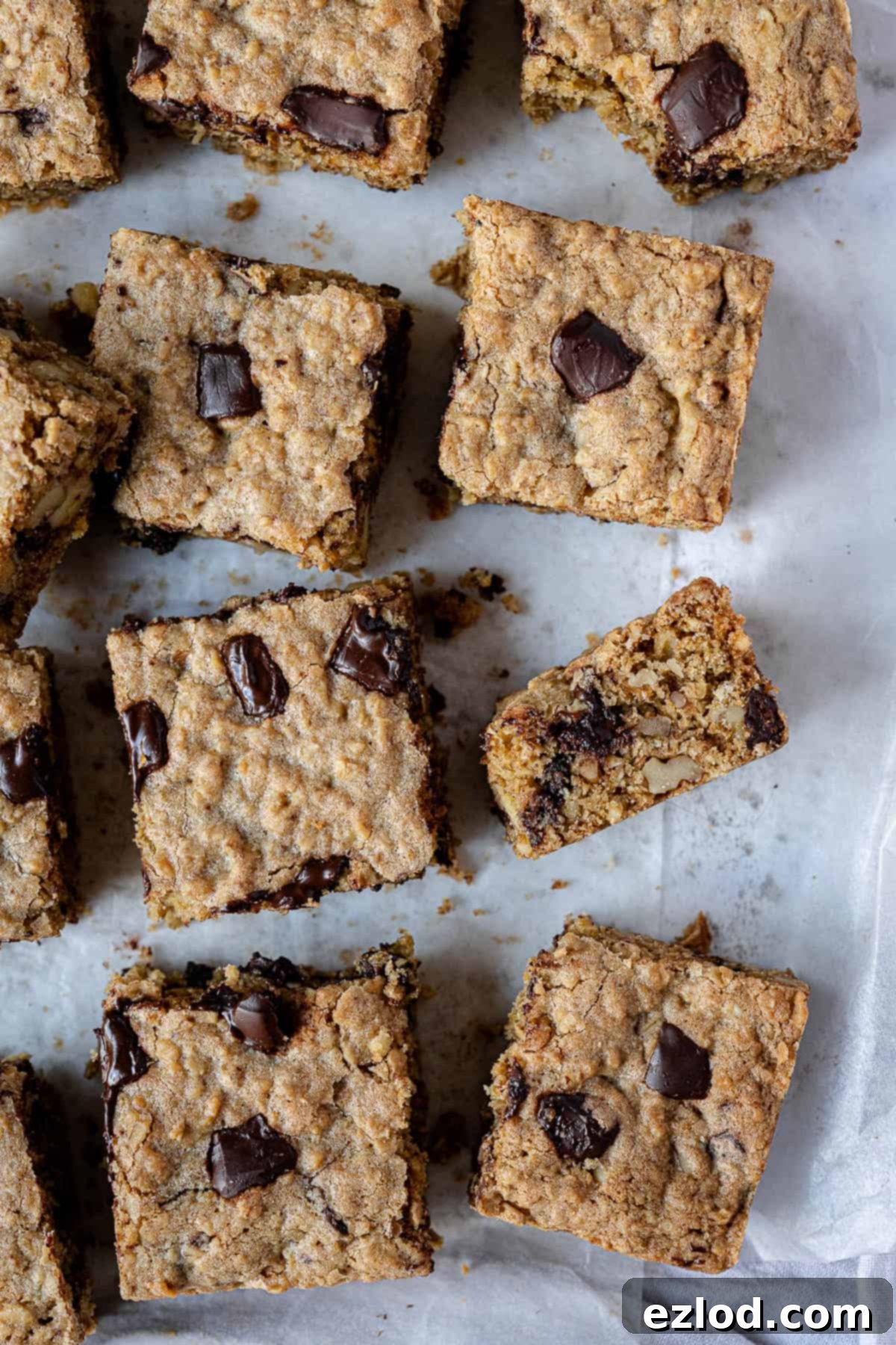 Close-up of freshly sliced vegan oatmeal cookie bars revealing their chewy texture, melted chocolate chunks, and walnut pieces.