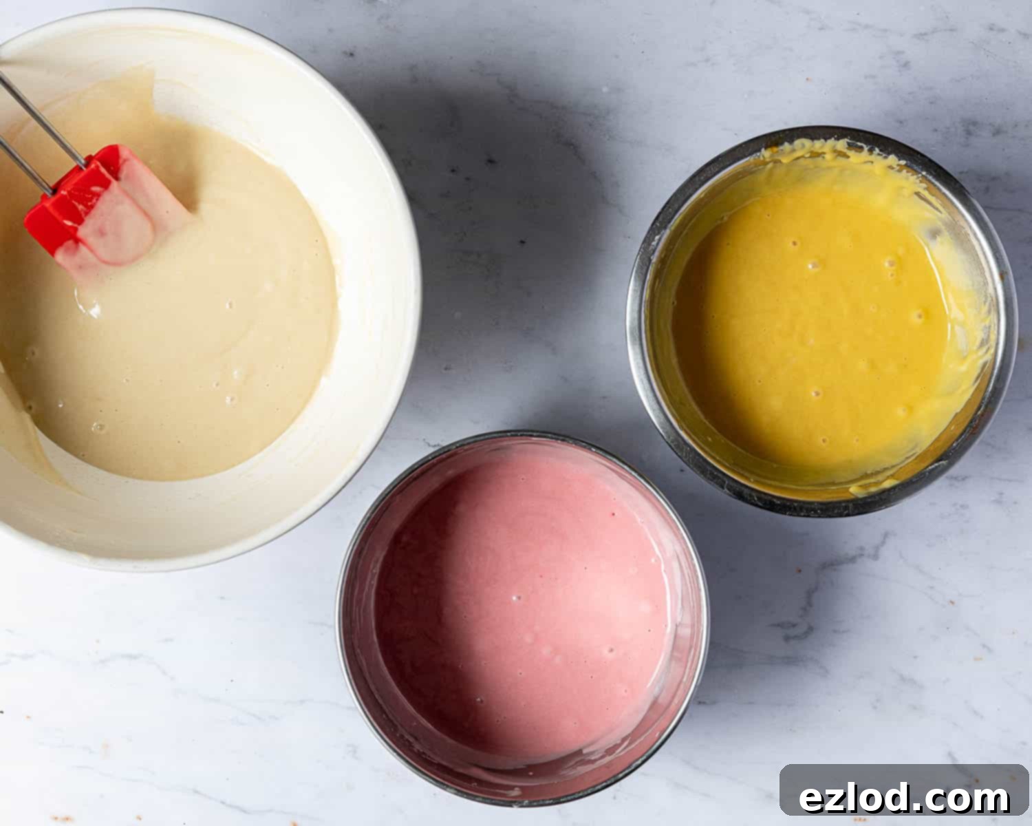 Step 2, the batter divided into three bowls and coloured yellow and pink.