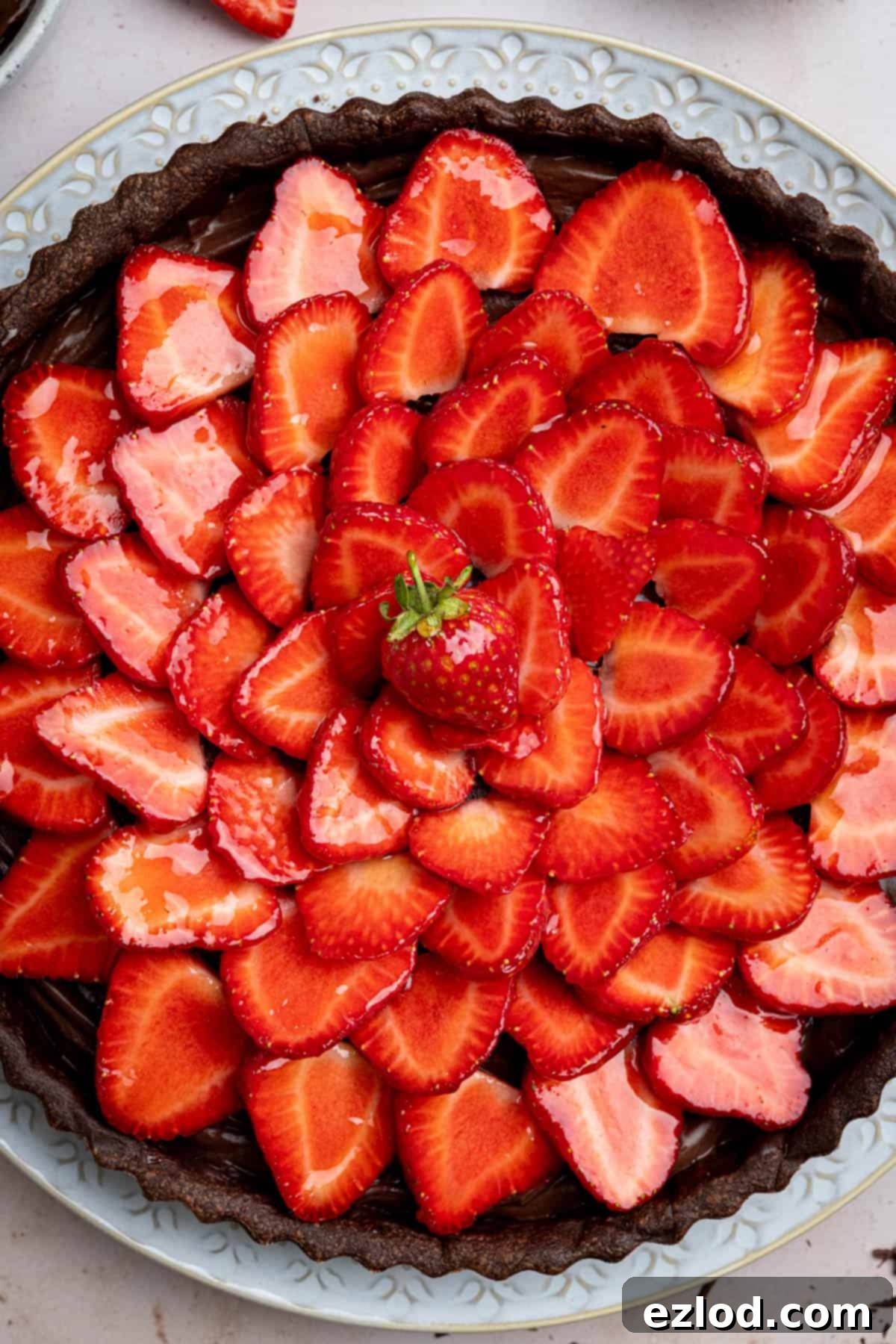 A close-up view of the perfectly arranged fresh strawberry slices on top of the chocolate strawberry tart, glistening with an apricot jam glaze.