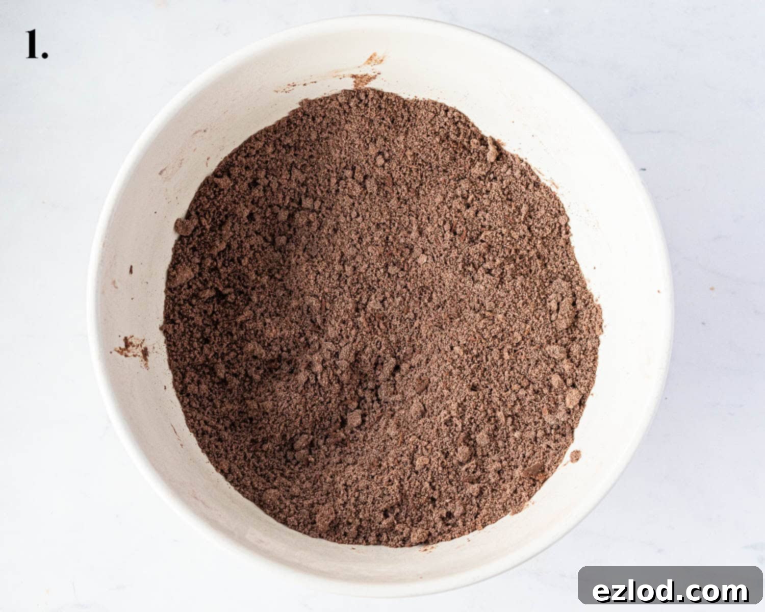 Step 1 in making chocolate strawberry tart: a bowl containing the sifted dry ingredients for the pastry with cold cubed vegan butter successfully rubbed in, resulting in a fine breadcrumb texture.
